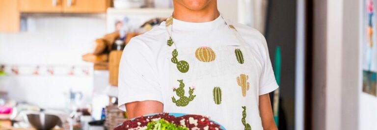 Mère et adolescent préparant des légumes ensemble dans une cuisine lumineuse