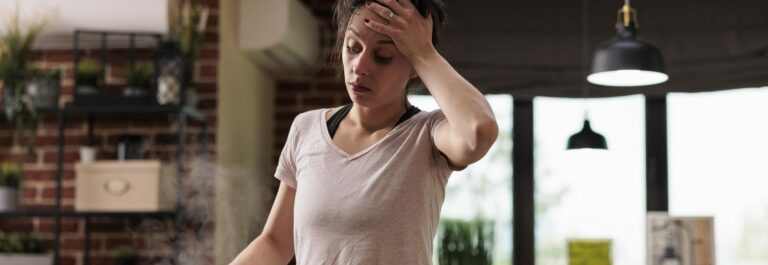Femme stressée tenant sa tête devant une pile de factures et un agenda
