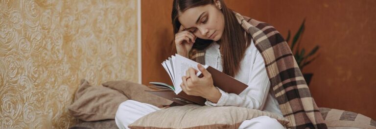 Femme souriante lisant un livre dans un intérieur chaleureux