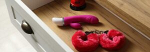 Vibromasseur posé sur une table de nuit en bois clair, ambiance douce et intime